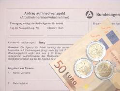 Das Bildzeigt einen Antrag auf Insolvenzgeld, auf dem zwei 50 Euro-Scheine und mehrere Euro-Münzen liegen