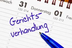 Das Bild zeigt einen Tischkalender, auf den mit blauer Schrift das Wort Gerichtsverhandlung geschrieben ist.